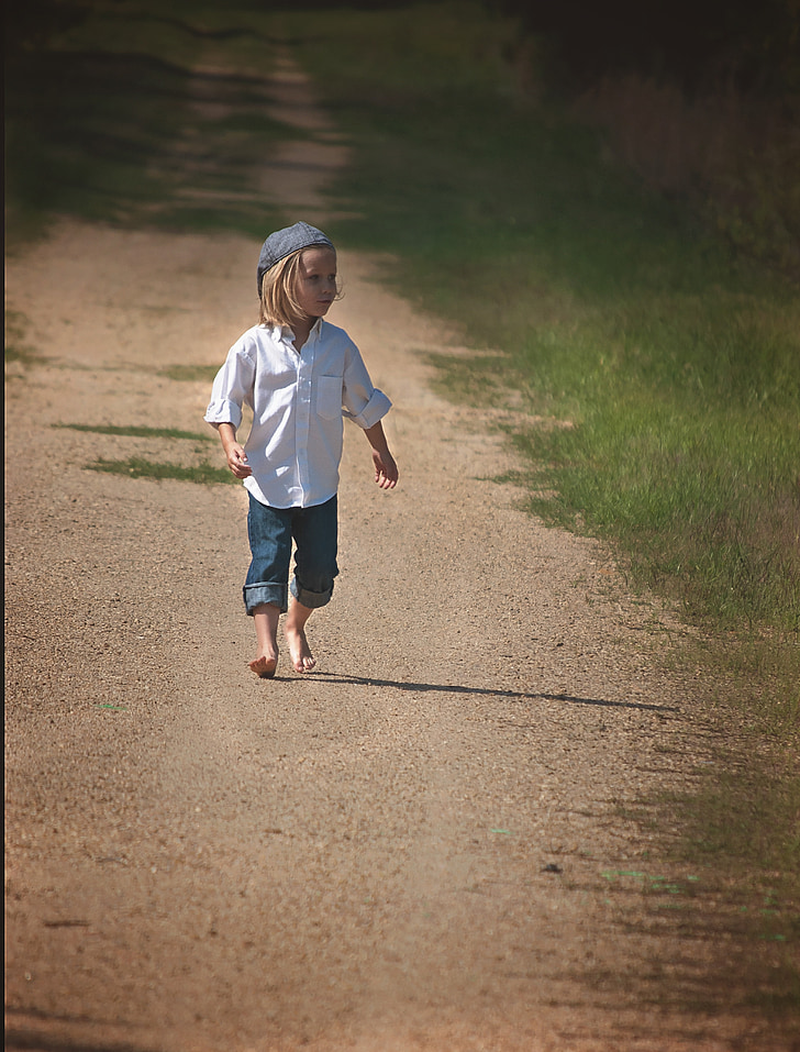 boy wearing white dress shirt and blue denim pants walking on sand during daytime