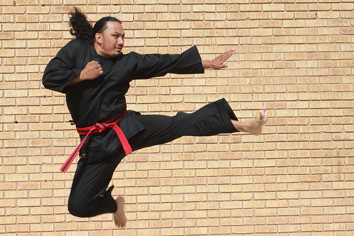 man in black karati gee doing flying kick