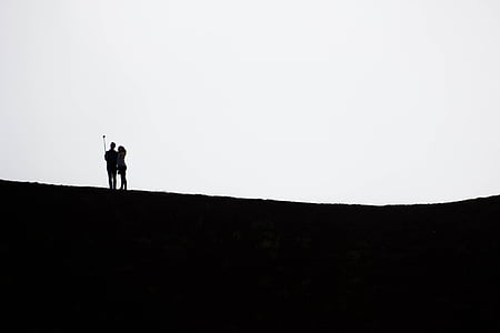 silhouette of woman and man holding monopod