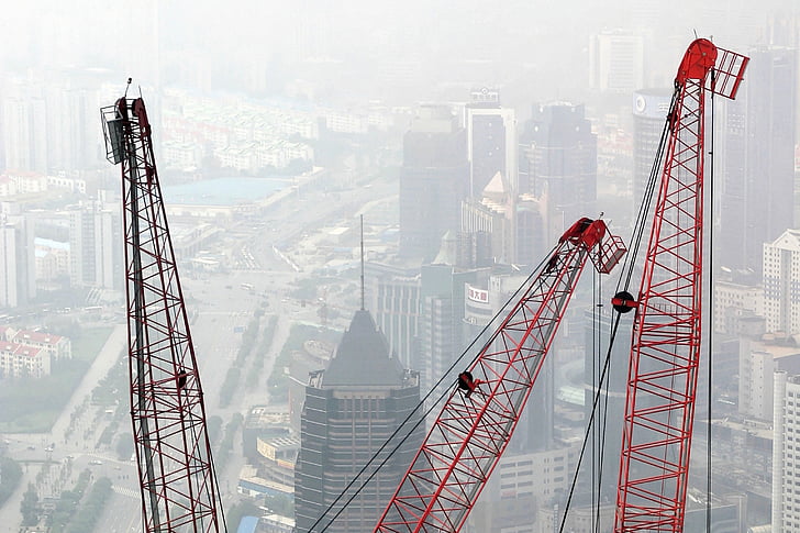 aerial photo of tower cranes beside high rise buildings