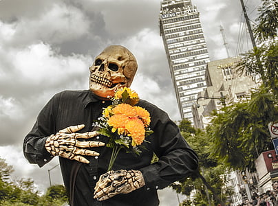 person in skeleton costume holding bouquet of yellow petaled flowers