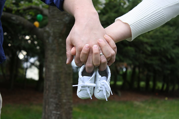 person holding pair of baby's white sneakers