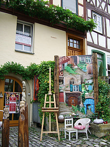brown easel stand beside painting in front of building