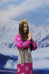 woman wearing pink and white floral dress standing near mountain background