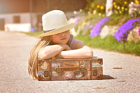 girl leaning on suitcase during daytime