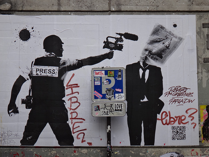 graffiti of man holding camera pointing to man in black suit jacket