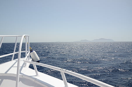 white boat with island at distance