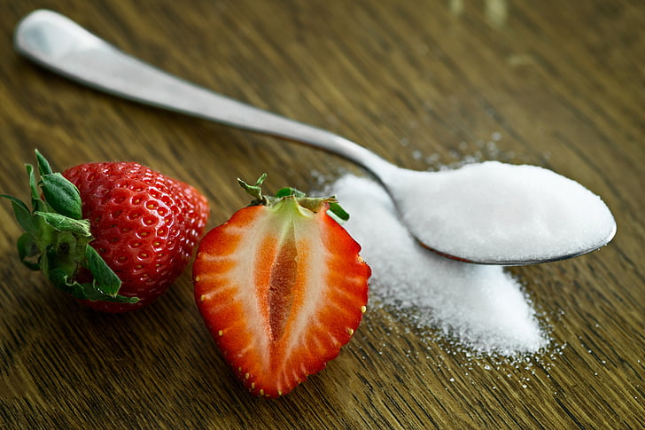 white spoon with white sugar and strawberry fruit
