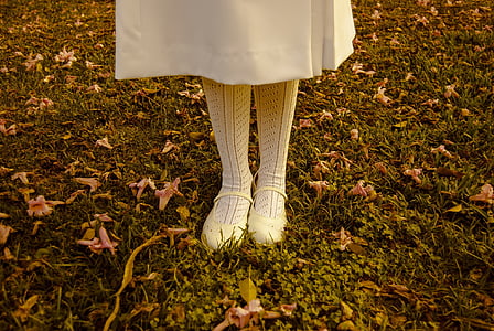 woman wearing white socks and white Mary Jane flats standing on grass field