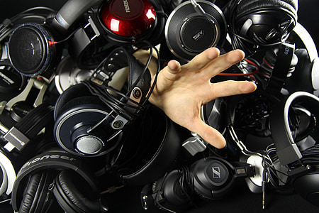 human hand surrounded by black and gray corded headphones