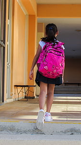 girl wearing backpack while walking on pathway
