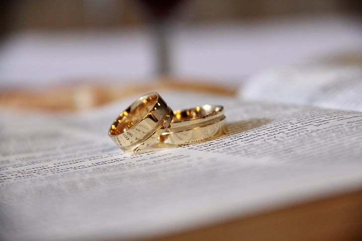 gold-colored wedding bands on bible