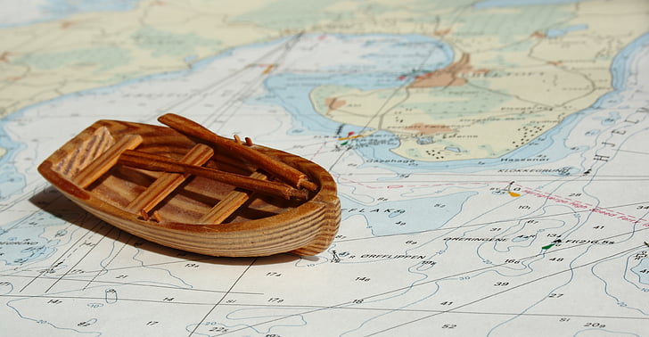 brown wooden miniature boat on top of map