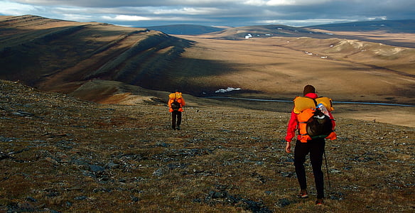 two men in red suits walking ind the middle of the land during daytime