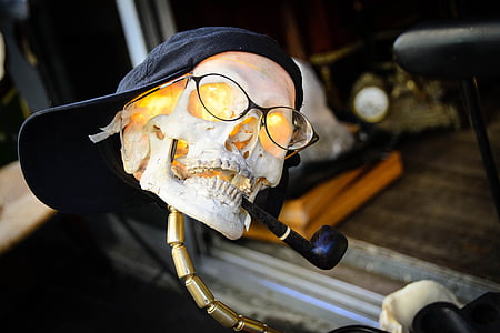 human skull decor with eyeglasses, cap, and tobacco pipe