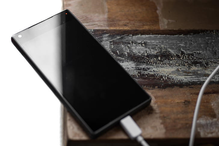 black smartphone on brown wooden surface