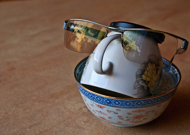 close photo of sunglasses on white ceramic tea cup