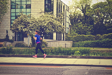 woman running along the street near building during daytime