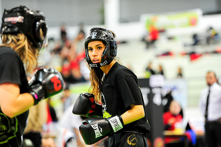 two woman wearing boxing sparing helmet and gloves