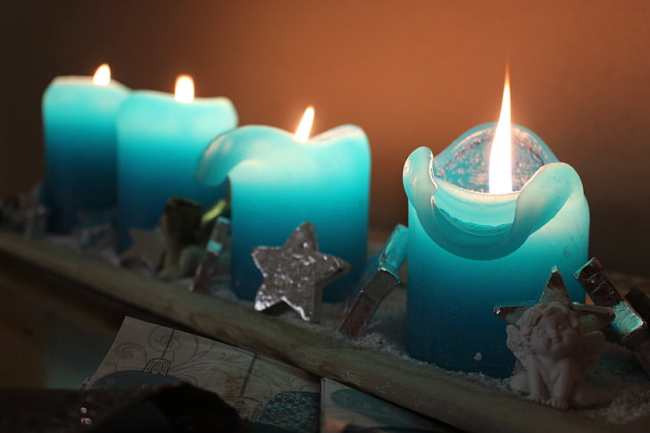 time lapse photography of four blue lighted candles