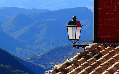 black lamppost on roof with mountains background