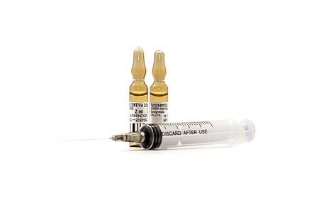 clear syringe with brown glass medication bottles