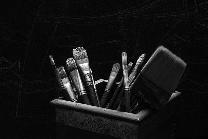 greyscale photo of paint brushes in box