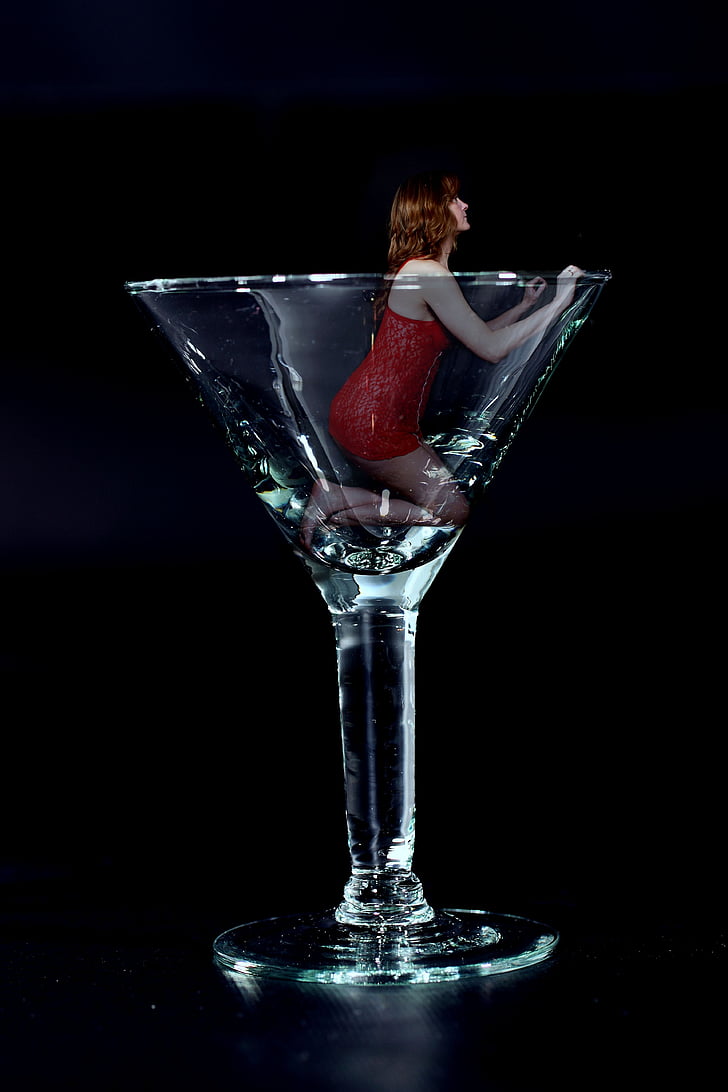 woman wearing red sleeveless dress in clear cocktail glass