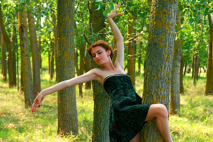 woman wearing black strapless dress making a pose in a forest