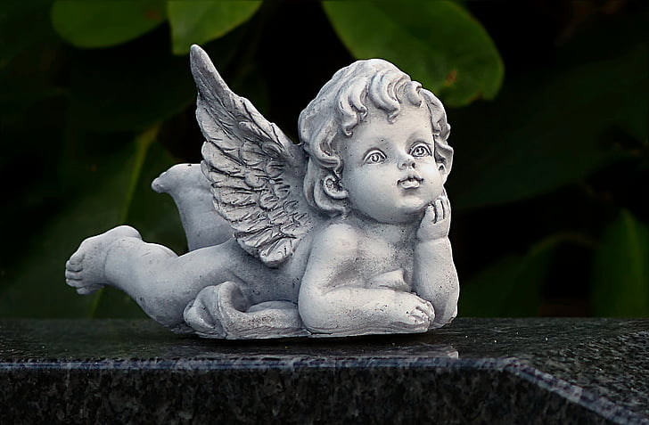 shallow focus photography of concrete cherub statue