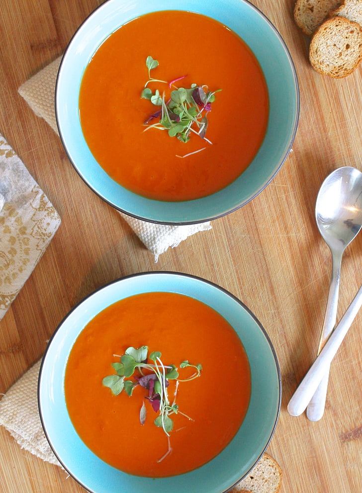 two orange soups on teal ceramic bowls