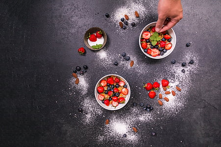 two round white and one brown bowls with strawberries and blue berries