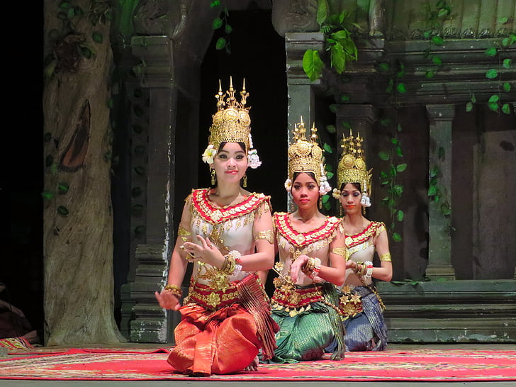 three kneeling women wearing traditional dresses