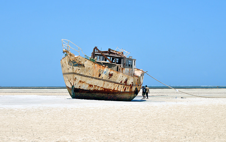 photo of white and brown ship on sand