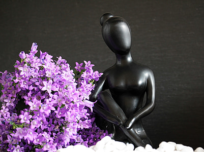 woman figurine beside purple flowers