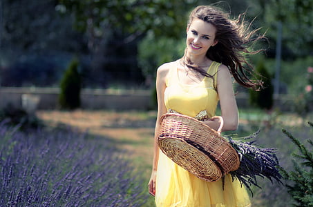 woman in yellow sleeveless dress carrying brown wicker basket