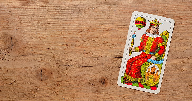 flat-lay photo of red and yellow dressed king card on brown desk