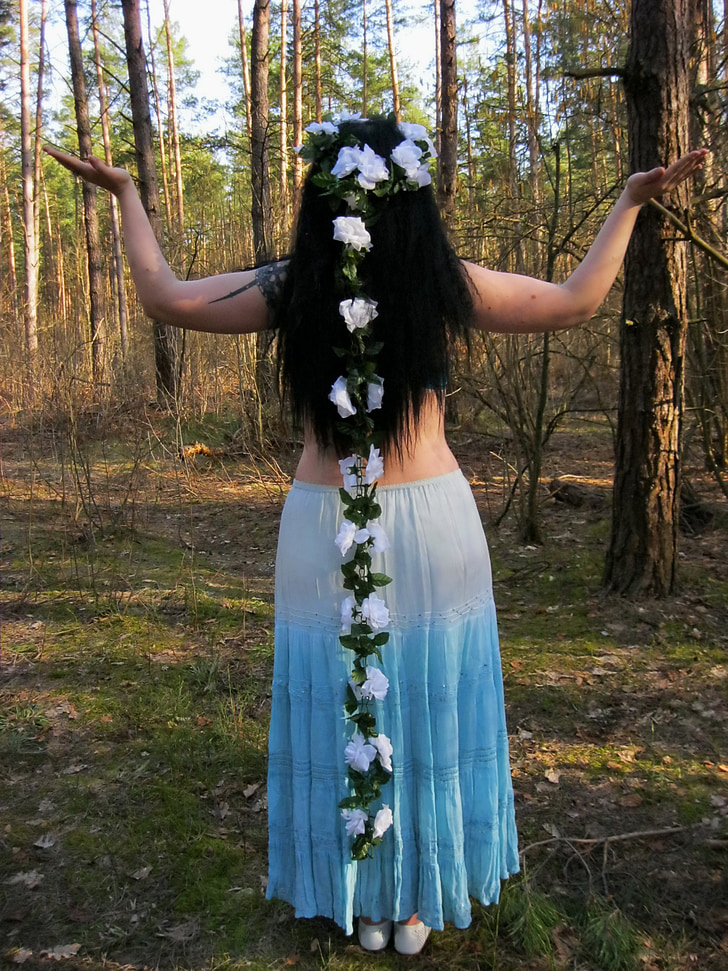 woman in blue and white skirt standing near trees during daytime
