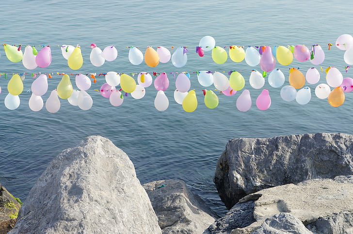balloon buntings over stone edge and ocean during day