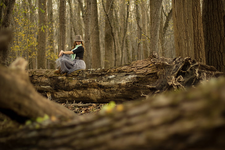 woman sitting on tree trunk at the middle of forest