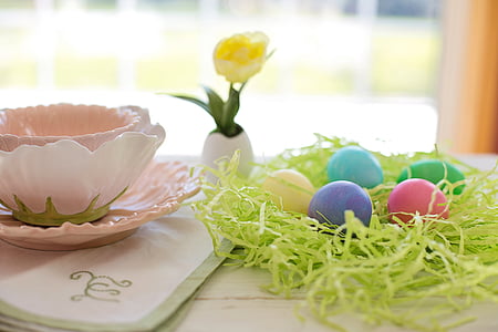 five assorted-color eggs on table beside a teacup on coaster