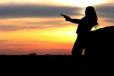 silhouette of girl holding revolver gun during golden hour