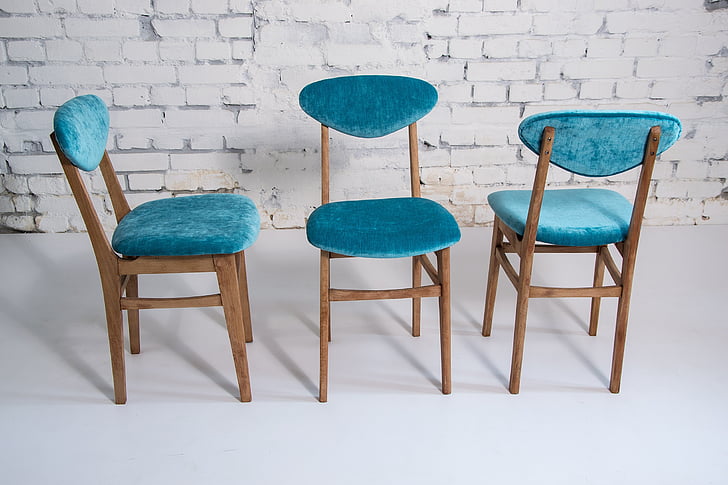 blue fabric chairs with brown wooden frame near white wall