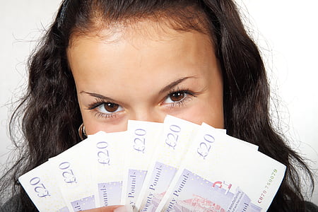 woman holding 20 English pound banknotes