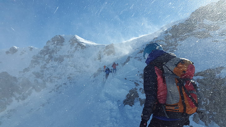 people climbing on snow capped mountain during daytime