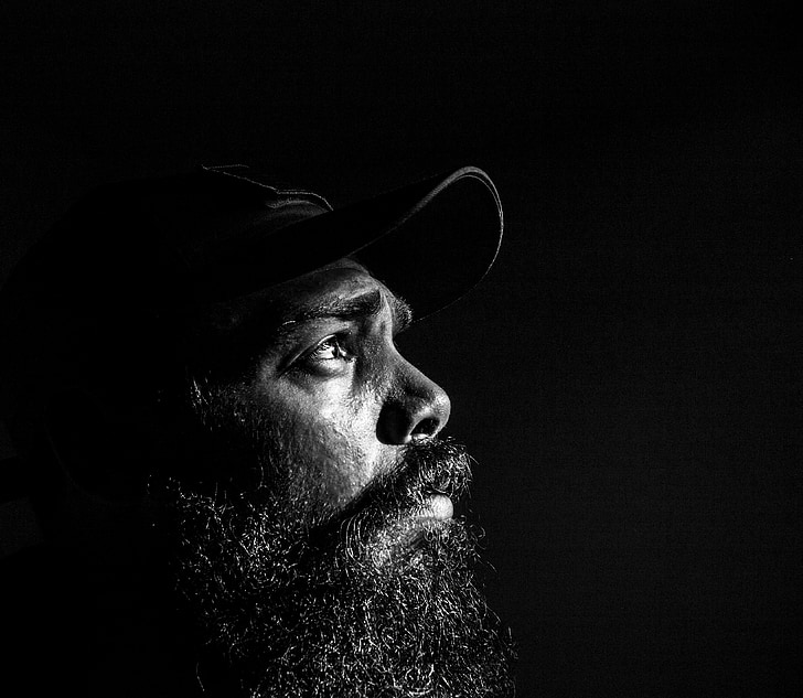 man with black beard wearing black cap on grayscale photography