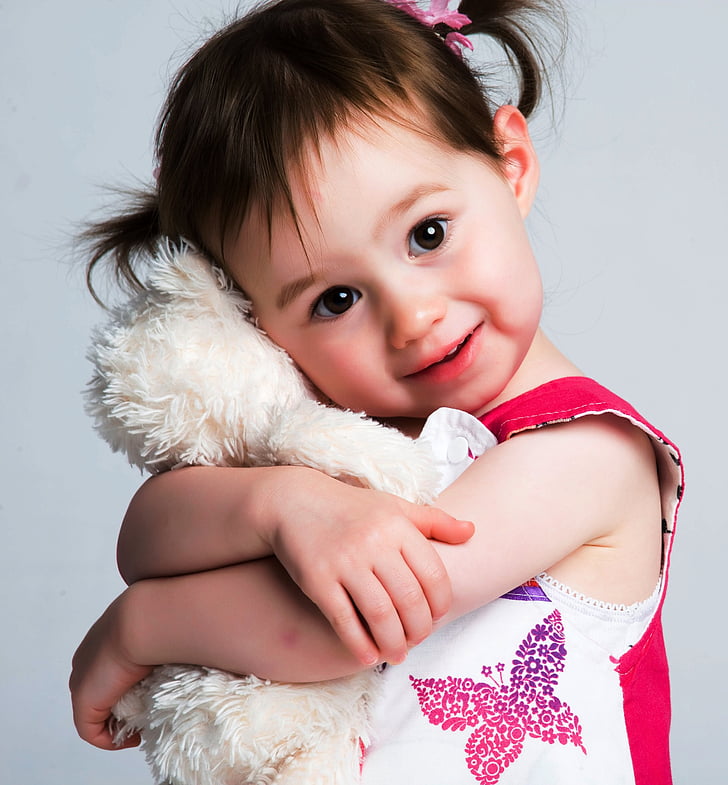 toddler wearing red top hugging white plush toy