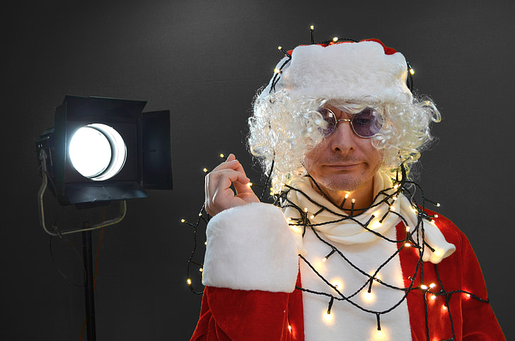 man wearing Santa Claus with string lights near black studio lamp