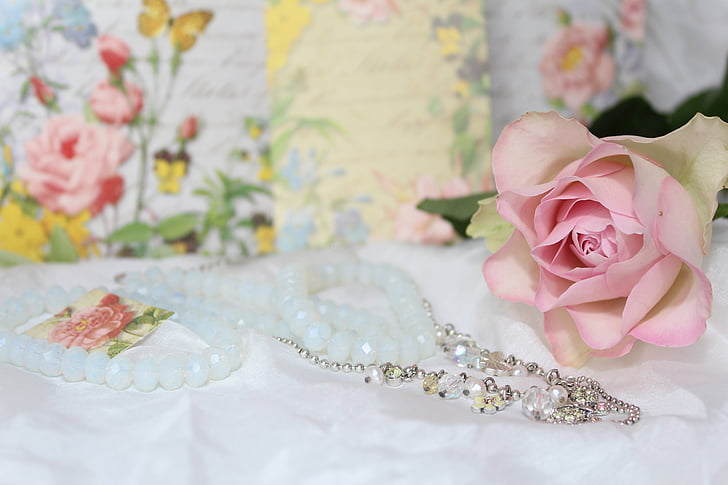 silver-colored necklace and pink rose