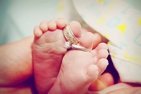 baby's feet with two silver-colored rings